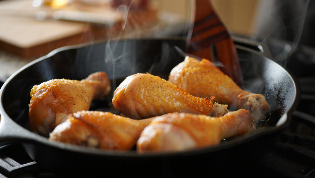 Pilons de Poulet au Paprika et Curcuma 4 Pilons de poulet rôtis au paprika fumé et curcuma, servis dans une poêle ou sur assiette, peau croustillante et dorée, accompagnements variés, scène de cuisine maison chaleureuse, style culinaire éditorial.